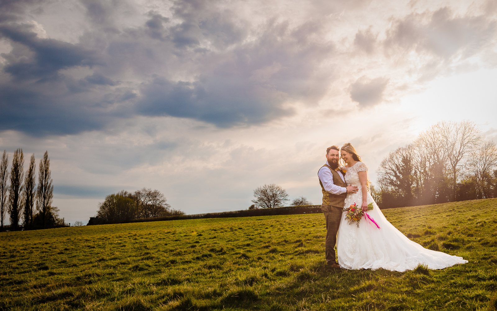 bride and groom standing in a field at silchester farm in the evening