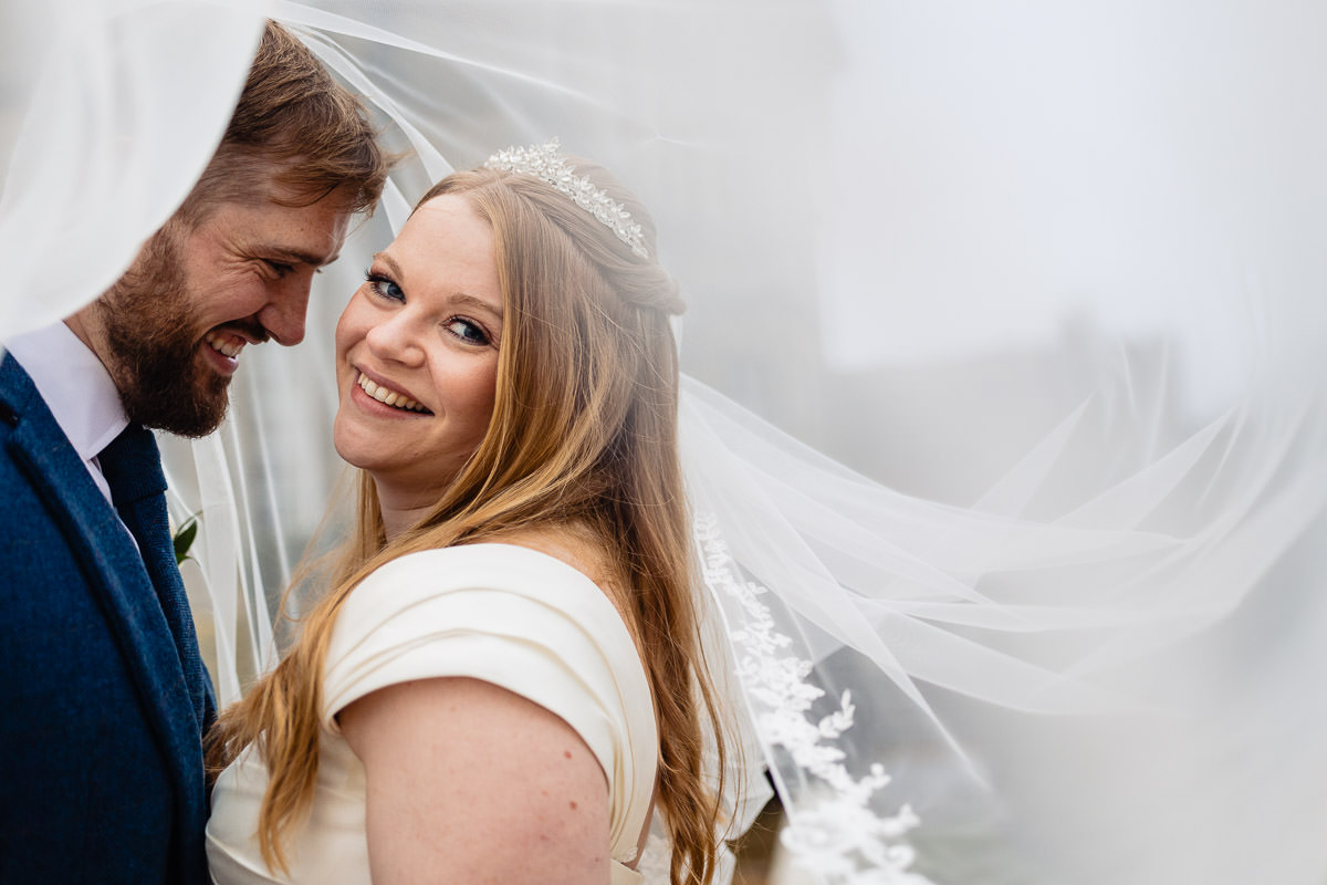 Hedsor House wedding3O8A1889Beautifullightukphotography close up of bride & groom under a veil. The bride is smiling at the camera