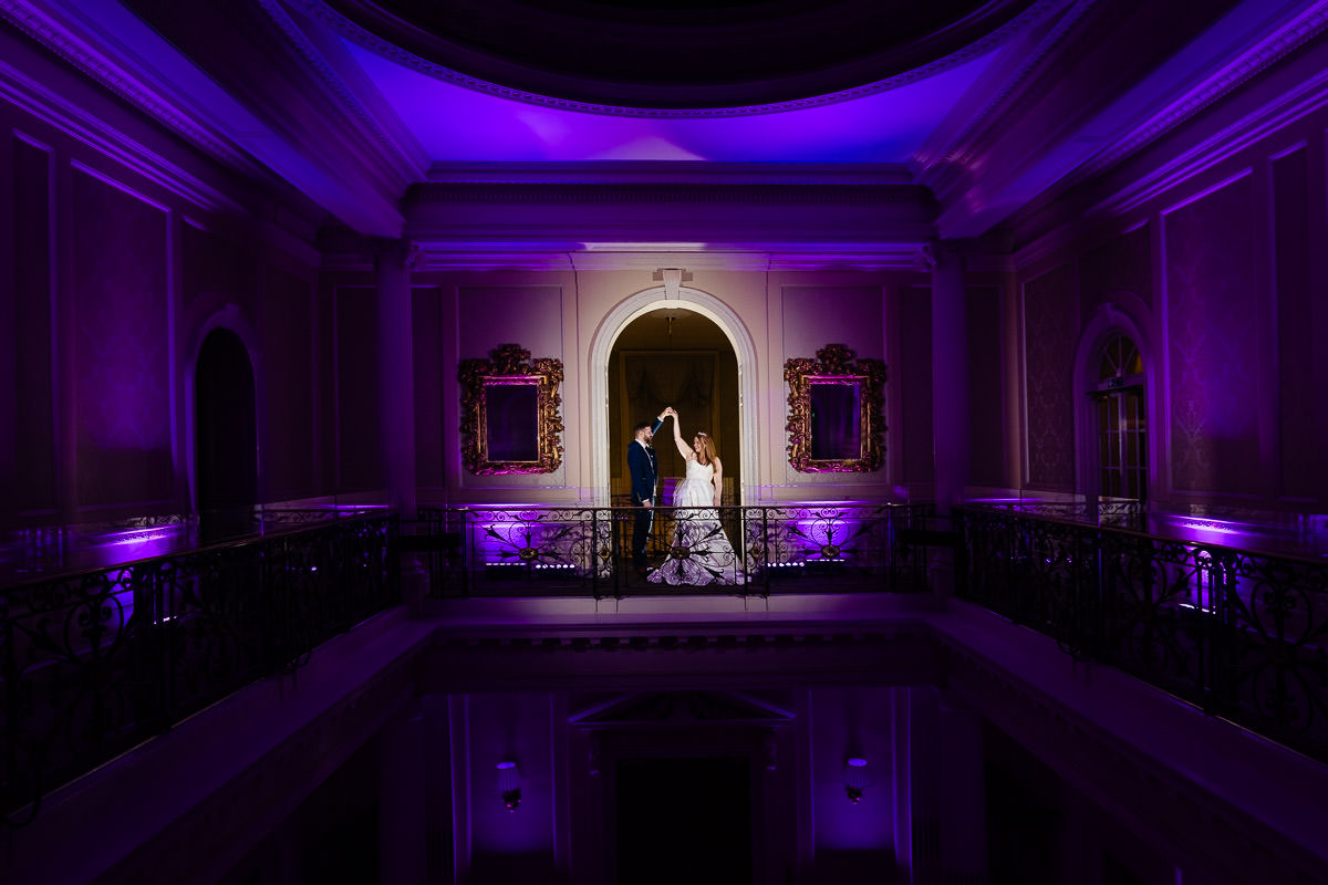 A portrait of a bride & groom dancing in the archway on the mezzanine at Hedsor House