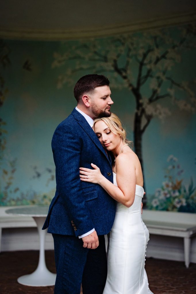 Portrait of a couple hugging in the Italian pavillion in the gardens at Wasing Park on their Summery wedding day